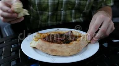 男人正在吃一道格鲁吉亚民族菜-卡查普里，相机运动。 他把一块面包撕下来蘸了蘸